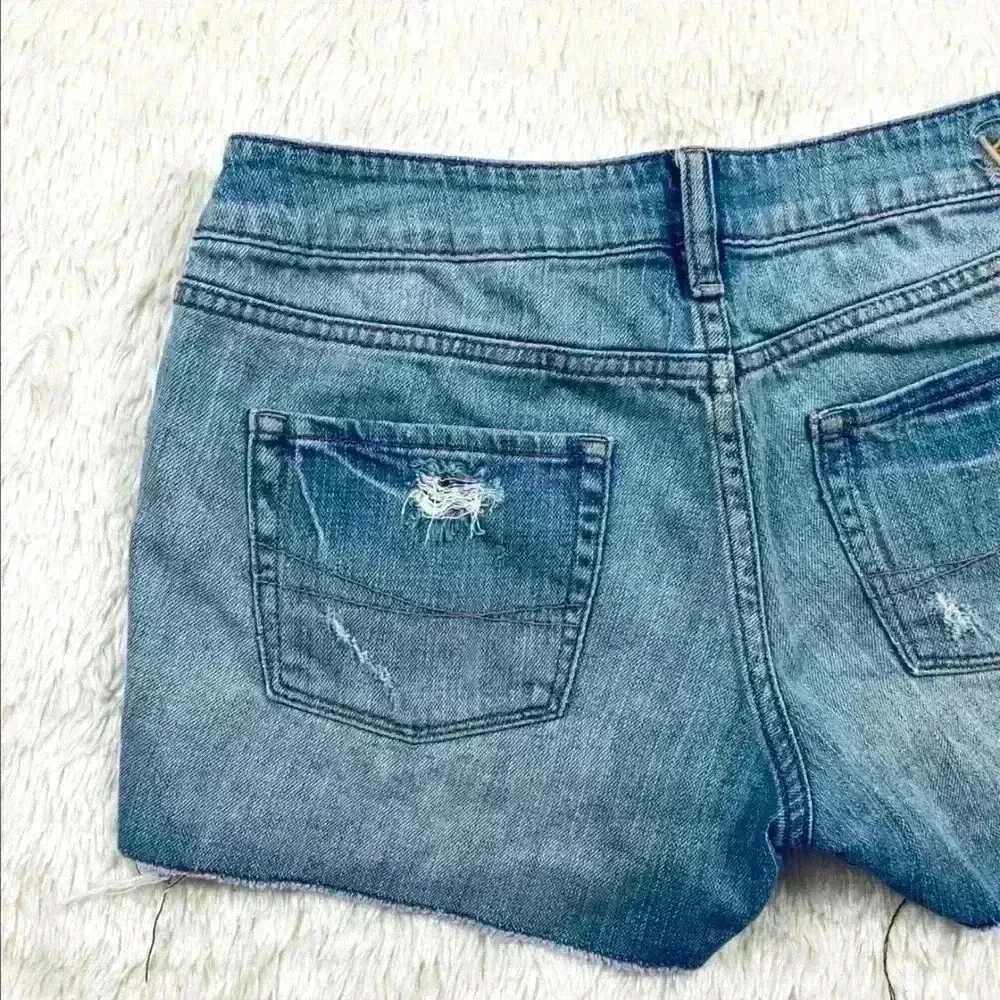 B By‎ Bullhead Med Wash Lowrise Distress Faded Cheeky Raw Hem Jean Shorts Size 9